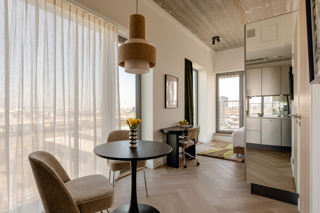 Serviced apartments Lichte, modern ingerichte serviced apartment in de Makerstoren met een zithoek, werkplek, houten visgraatvloer en panoramisch uitzicht over Amsterdam.