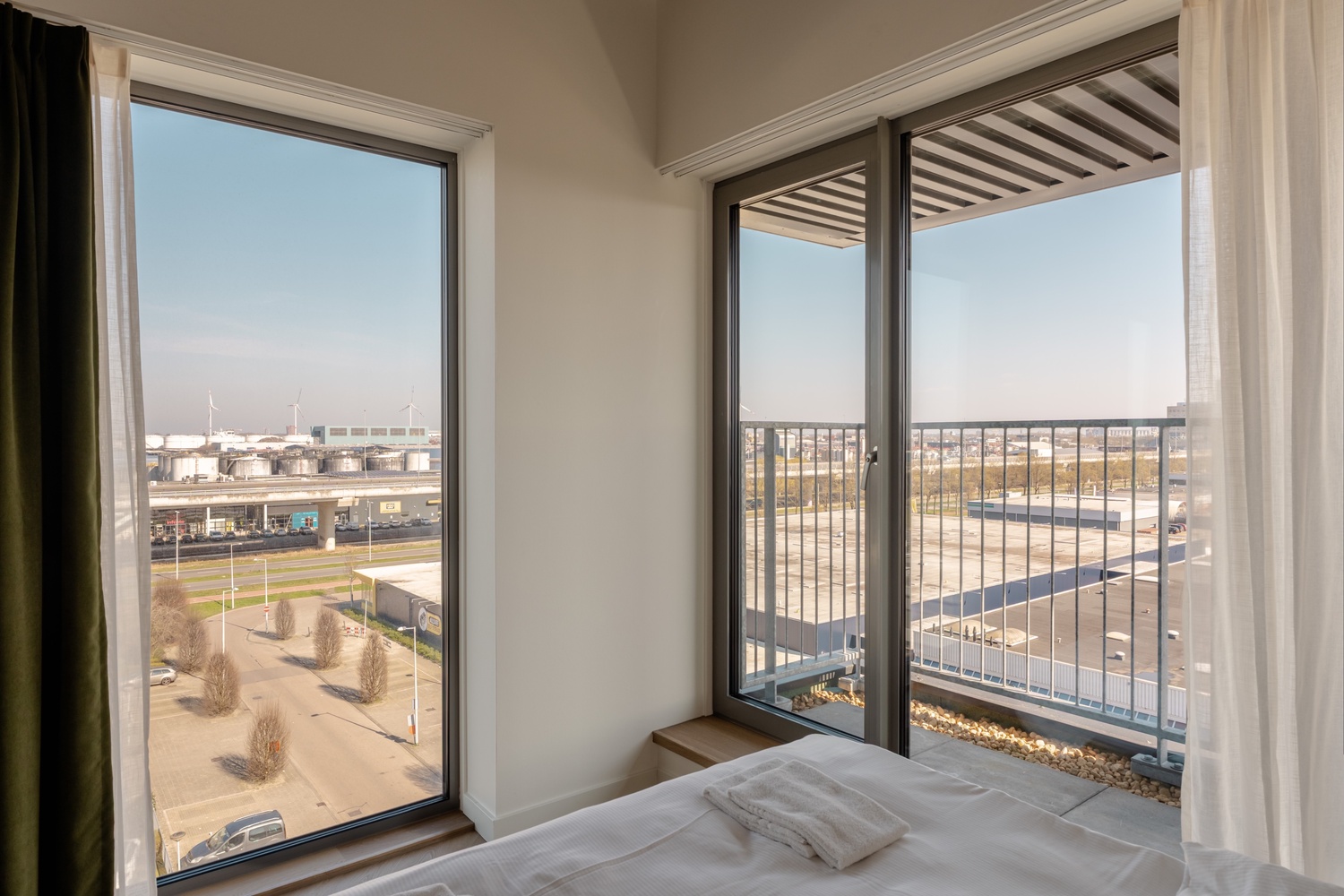 Slaapkamer van de Superior Studio with Balcony in Makerstoren, met balkondeur en uitzicht over de haven van Amsterdam