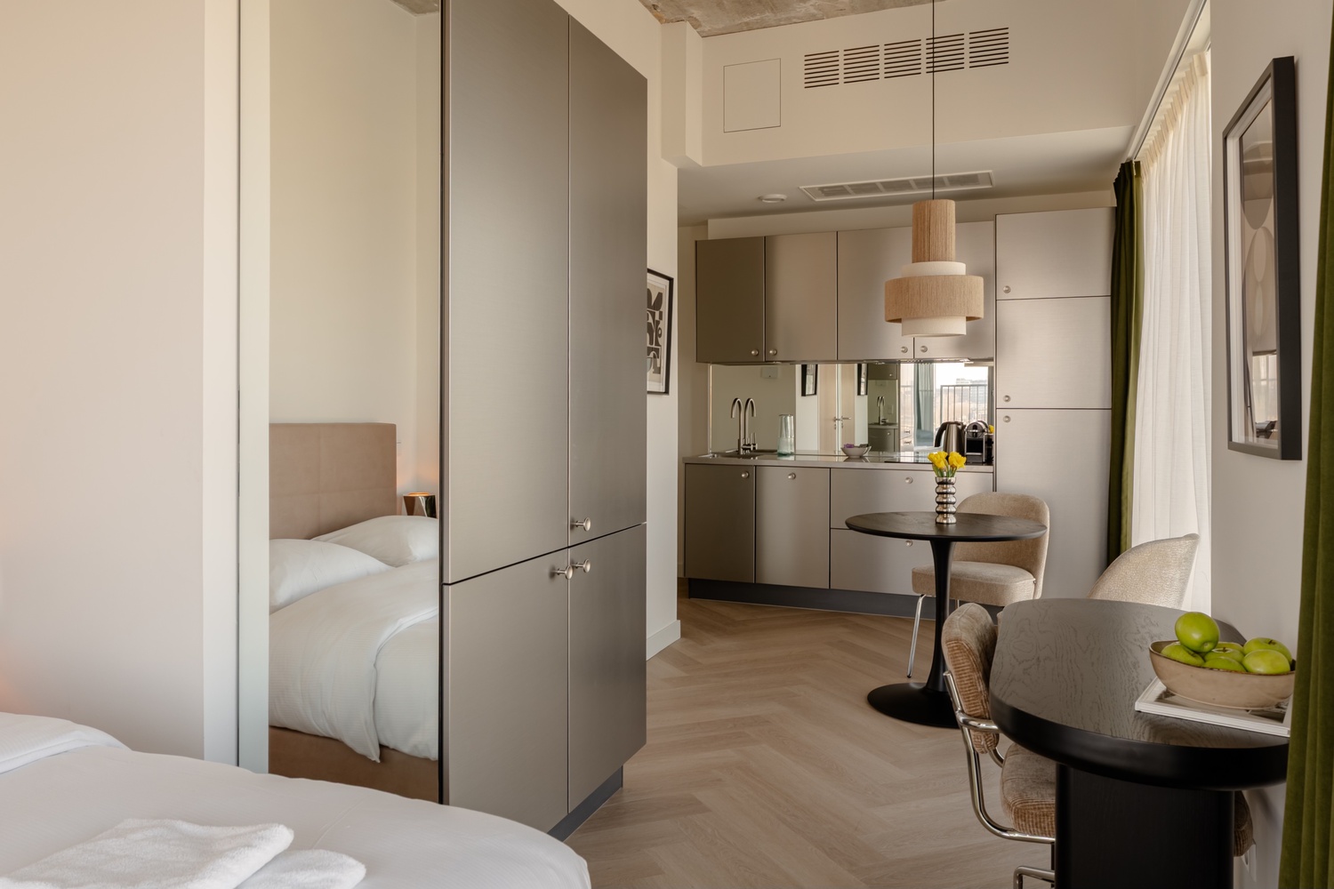 Doorkijk met spiegelkast, bed en keuken in de Superior Studio with Balcony van Makerstoren