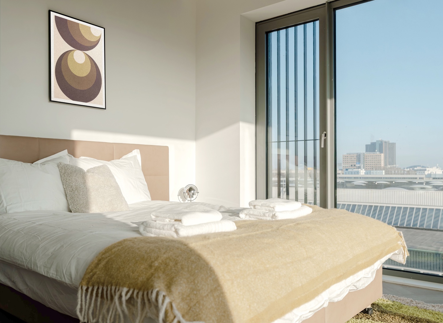 Tweepersoonsbed in de Executive Studio City View van Makerstoren, met groot raam en uitzicht op de skyline van Amsterdam