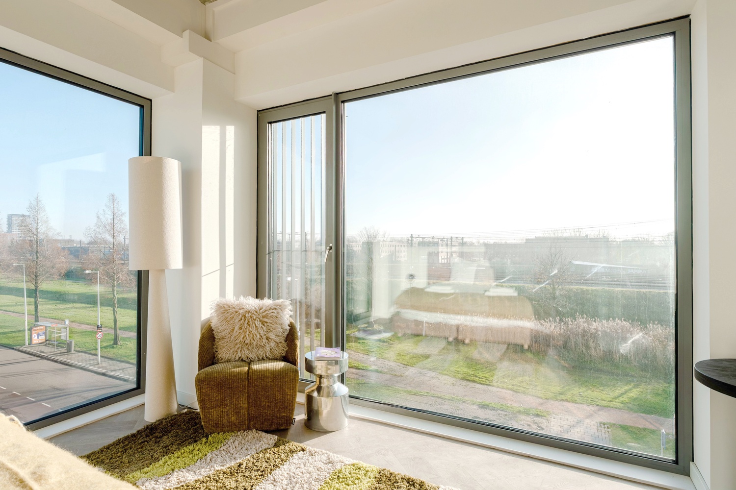 Hoekraam met fauteuil in de Executive Studio City View van Makerstoren, met uitzicht over de omgeving van Amsterdam Sloterdijk