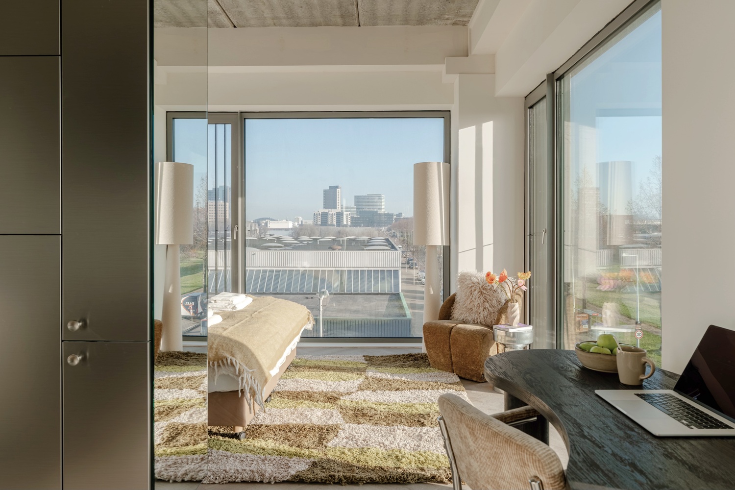 Executive Studio City View in Makerstoren met bed, bureau en uitzicht op de skyline van Amsterdam