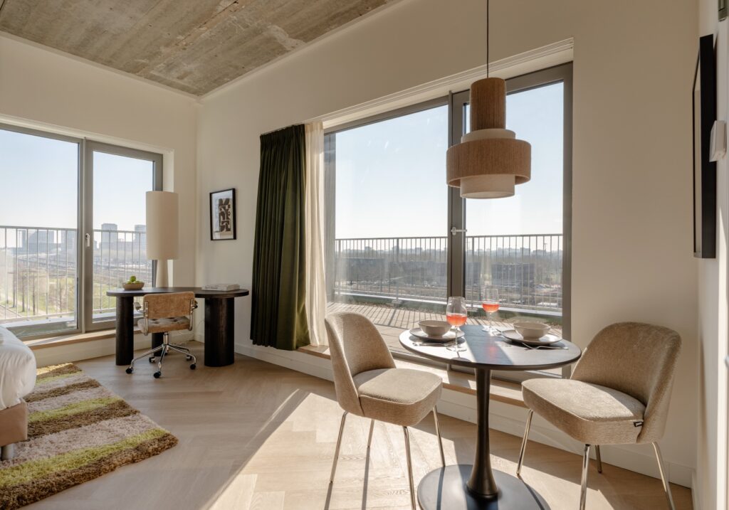 Zithoek met bureau en eettafel bij het raam in een Makerstoren appartement, met balkon en uitzicht over Amsterdam Sloterdijk