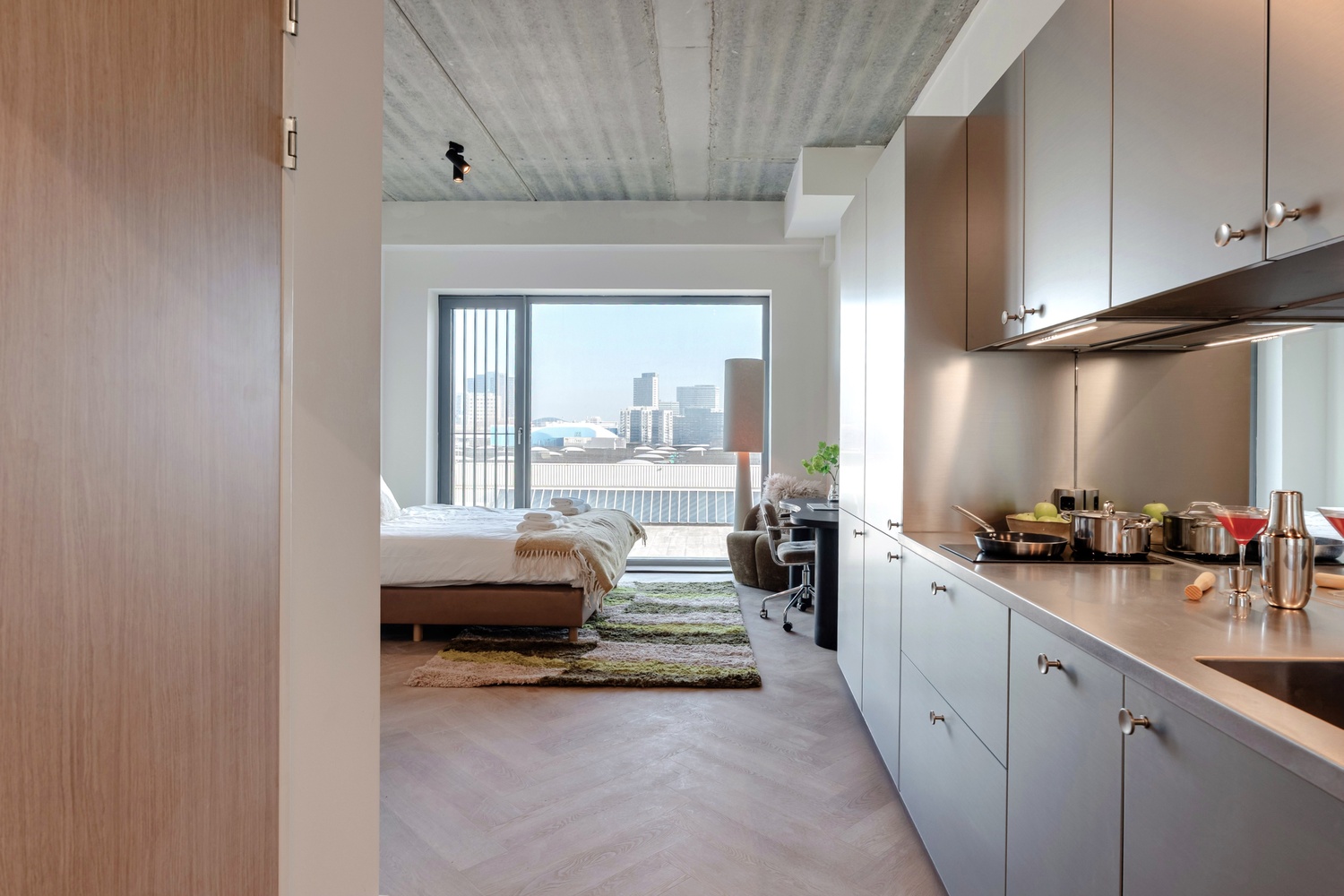 Doorkijk vanuit de keuken naar het bed en bureau in de Superior Studio van Makerstoren