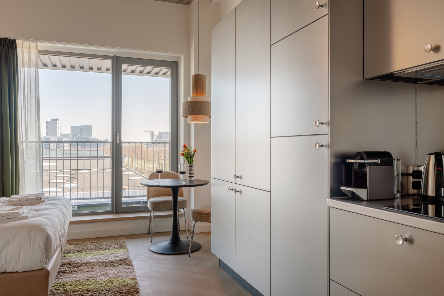 Eethoek bij de balkondeur van de Standard Studio with Balcony, met uitzicht op de skyline van Amsterdam