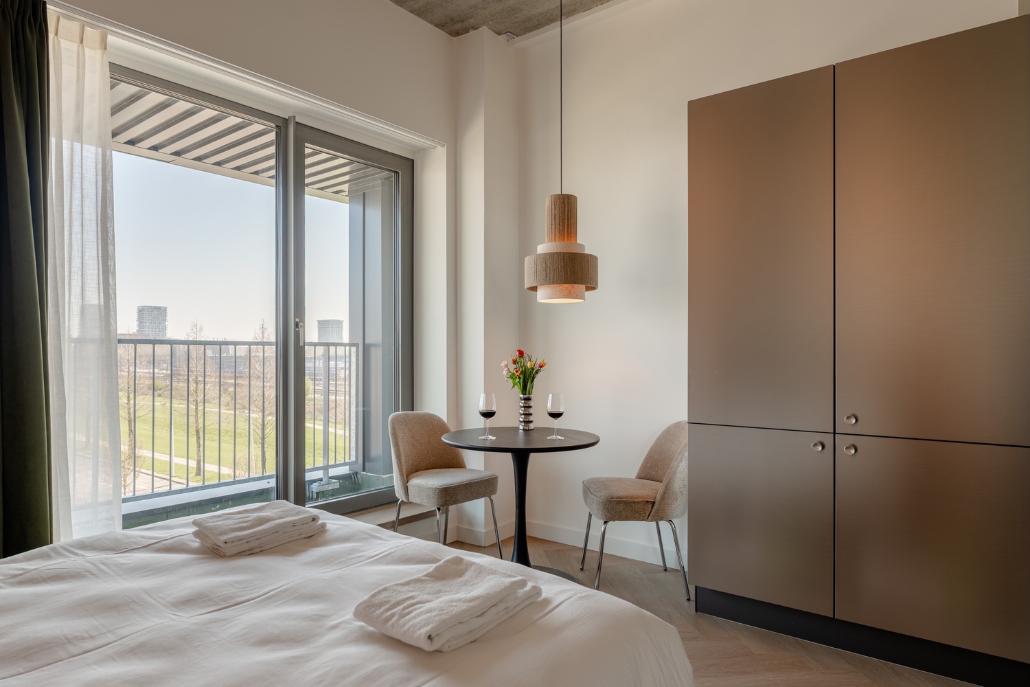 Handdoeken op het bed bij de balkondeur van de Standard Studio with Balcony, met kledingkast en eethoek