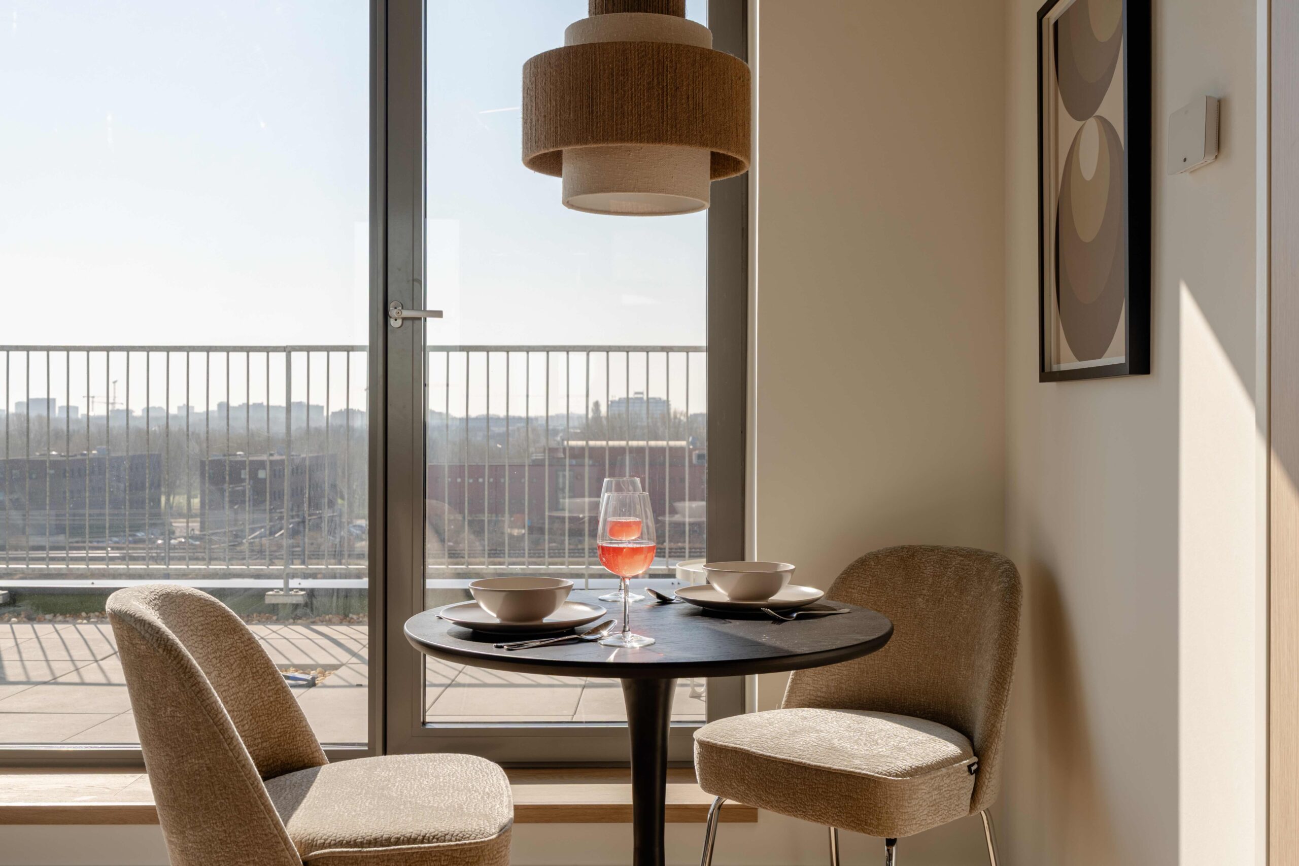 Ronde eettafel met wijnglazen en uitzicht op Amsterdam vanaf balkon short-stay appartement Executive Corner