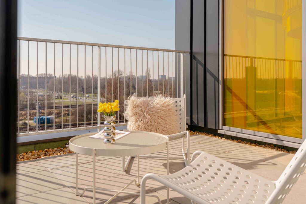Serviced apartments Loungehoek terras short-stay appartement Amsterdam – Executive Corner met kussen, tulpen en gele gevel