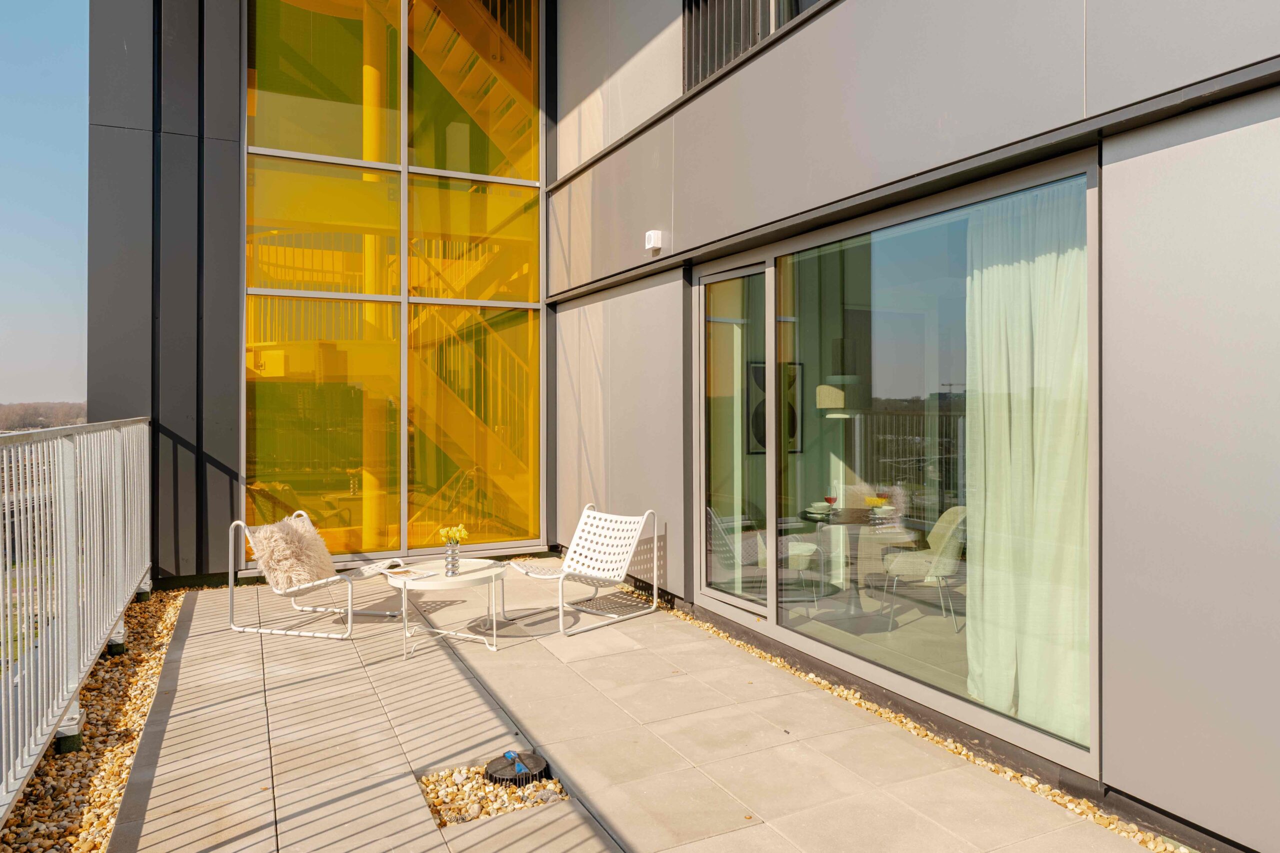 Terras met loungestoelen short-stay appartement Amsterdam – Executive Corner, uitzicht op balkon en gele gevel