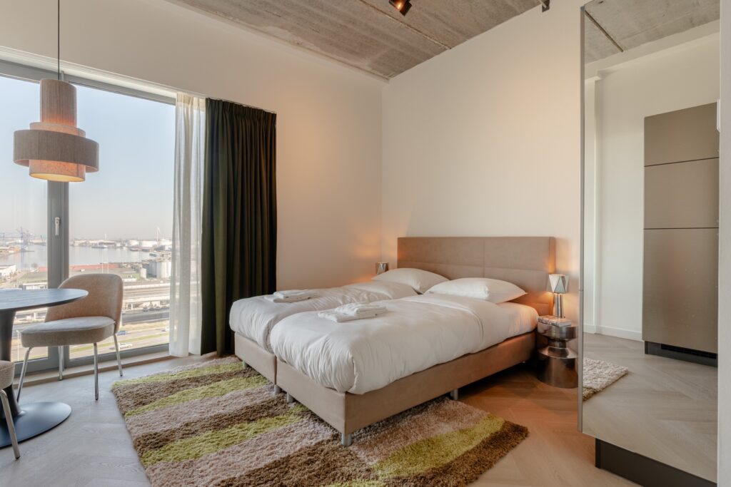 Tweepersoonsbed in de Standard Studio van Makerstoren met panoramisch uitzicht over de haven van Amsterdam